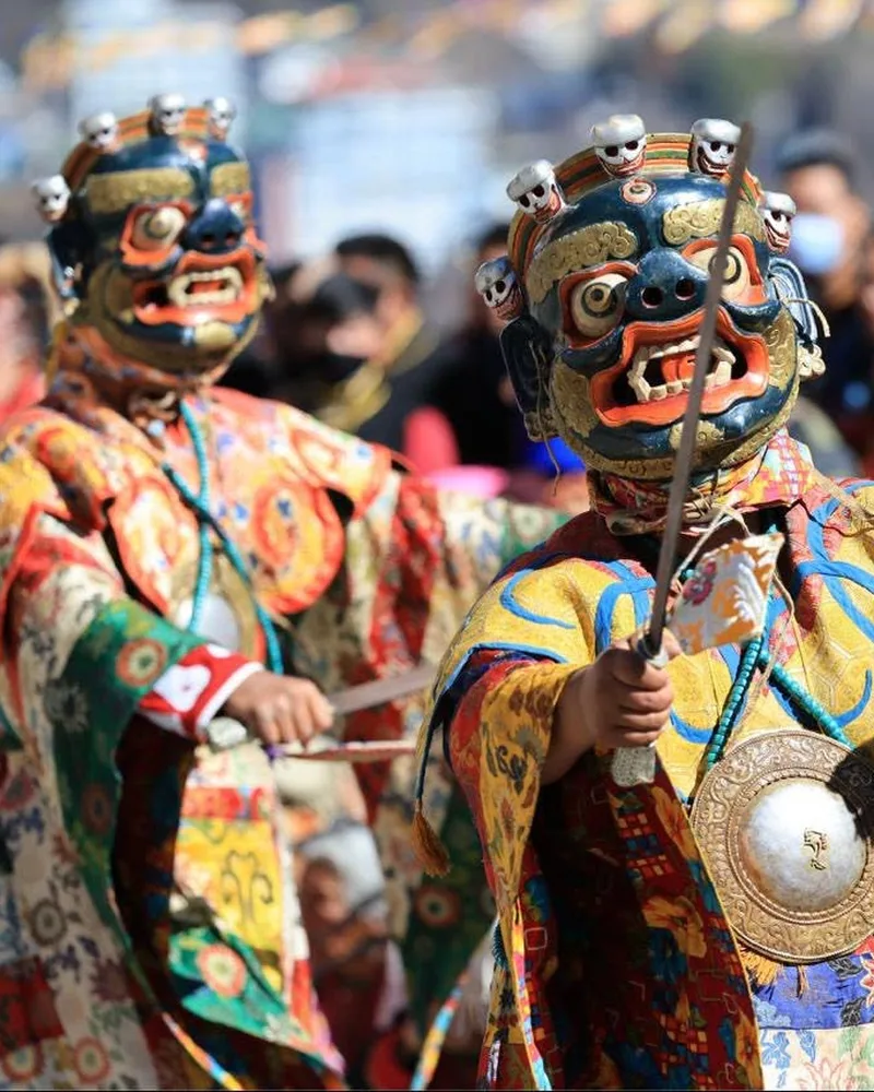 Skull-crowned cham dancers in brocade robes at the Torgya festival