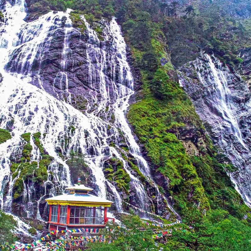 Nuranang Falls dropping past a small roadside gompa