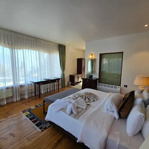 Timilo Classic — white linens, a green headboard and a wide bright window