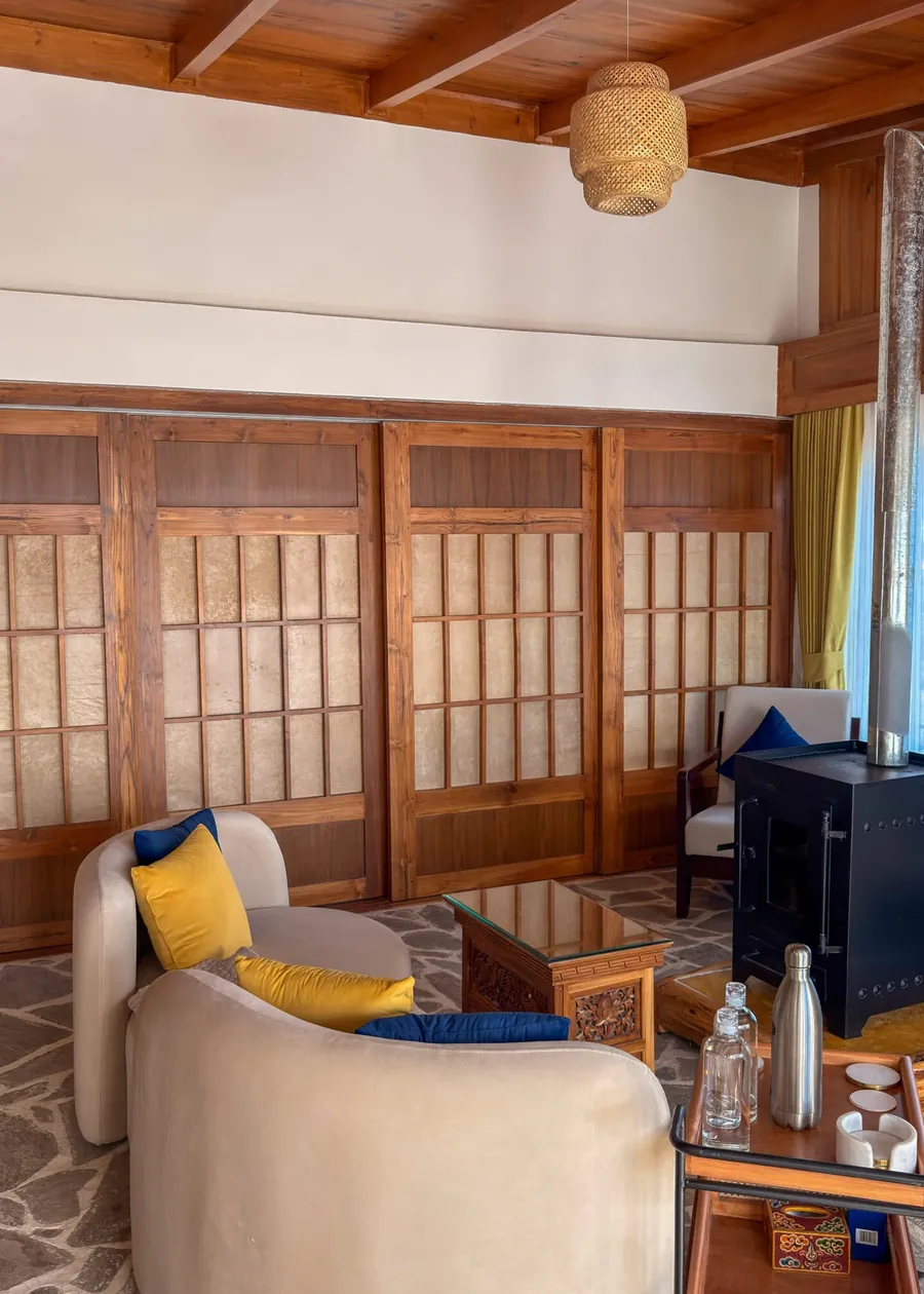 The Presidential Suite sitting room — curved sofas, shoji screens and a wood stove under a pine ceiling
