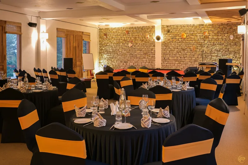The banquet hall set for an event, stone wall and warm wood beams above