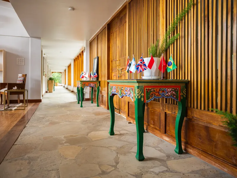 A covered corridor lined with prayer-flag-topped Monpa console tables