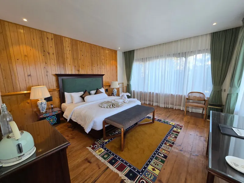 The room from the dresser — rug, armchair and the window beyond — Timilo Classic, Timilo Boutique