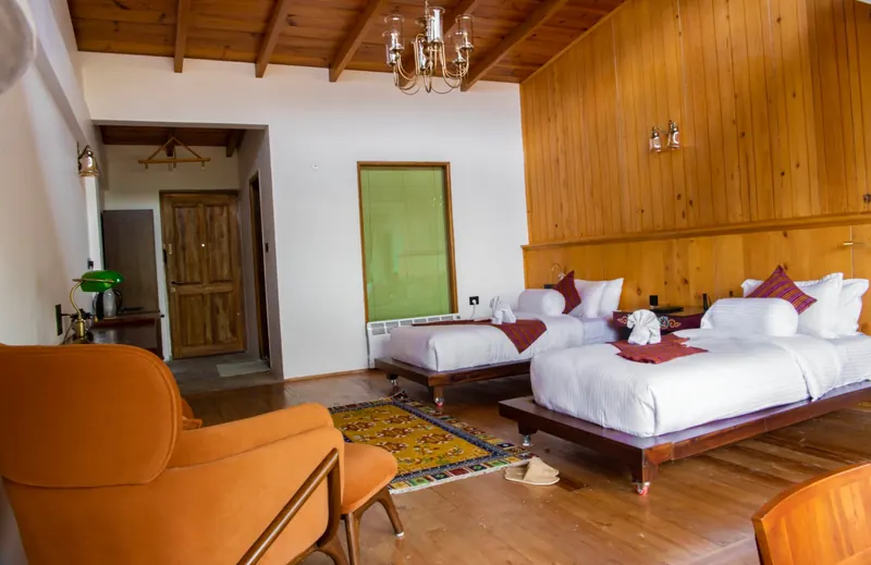 The green panel wall and a low armchair beside the beds — Timilo Royal Twin, Timilo Boutique