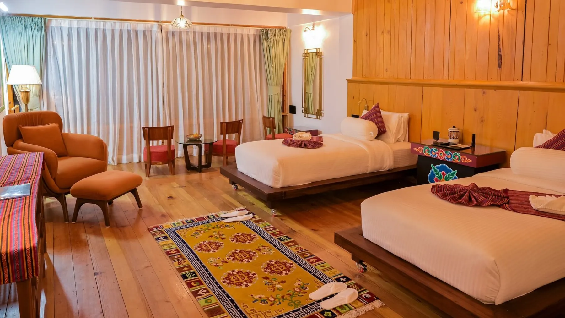 The Timilo Royal Twin — two beds under a pine ceiling with Tibetan rugs underfoot